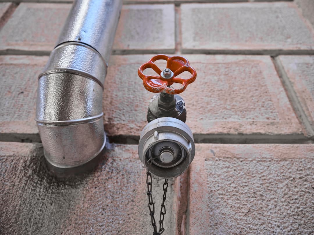 Robinet et canalisation en métal dans un cadre de mur en briques, démontrant l'équipement sanitaire d'un bâtiment.